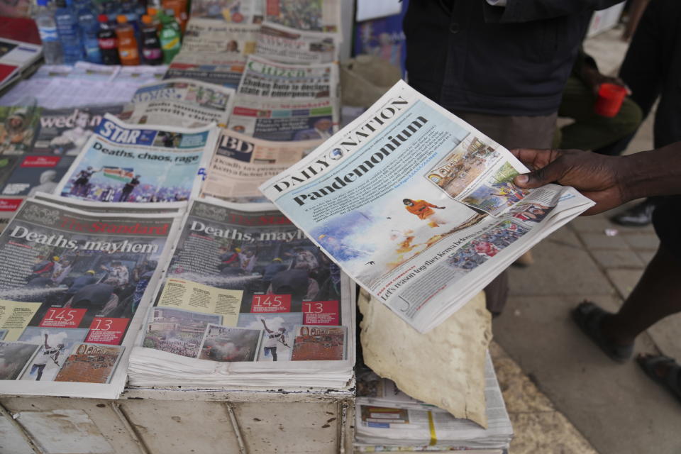 Kenyans discuss yesteday's protest as they read newspapers from a street vendor in downtown Nairobi, Kenya Wednesday, June 26, 2024. Thousands of protesters stormed and burned a section of Kenya's parliament Tuesday to protest tax proposals. Police responded with gunfire and several protesters were killed. (AP Photo/Brian Inganga)