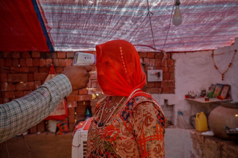 2021年4月8日，印度城市艾哈邁達巴德，一名醫護人員位一名預備接種疫苗的女士量度體溫。