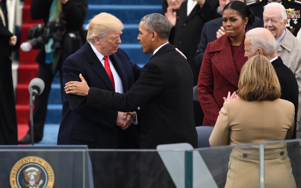 President Donald Trump, left, shakes hands with former U.S. President Barack Obama, watched by First Lady Michelle Obama - Bloomberg