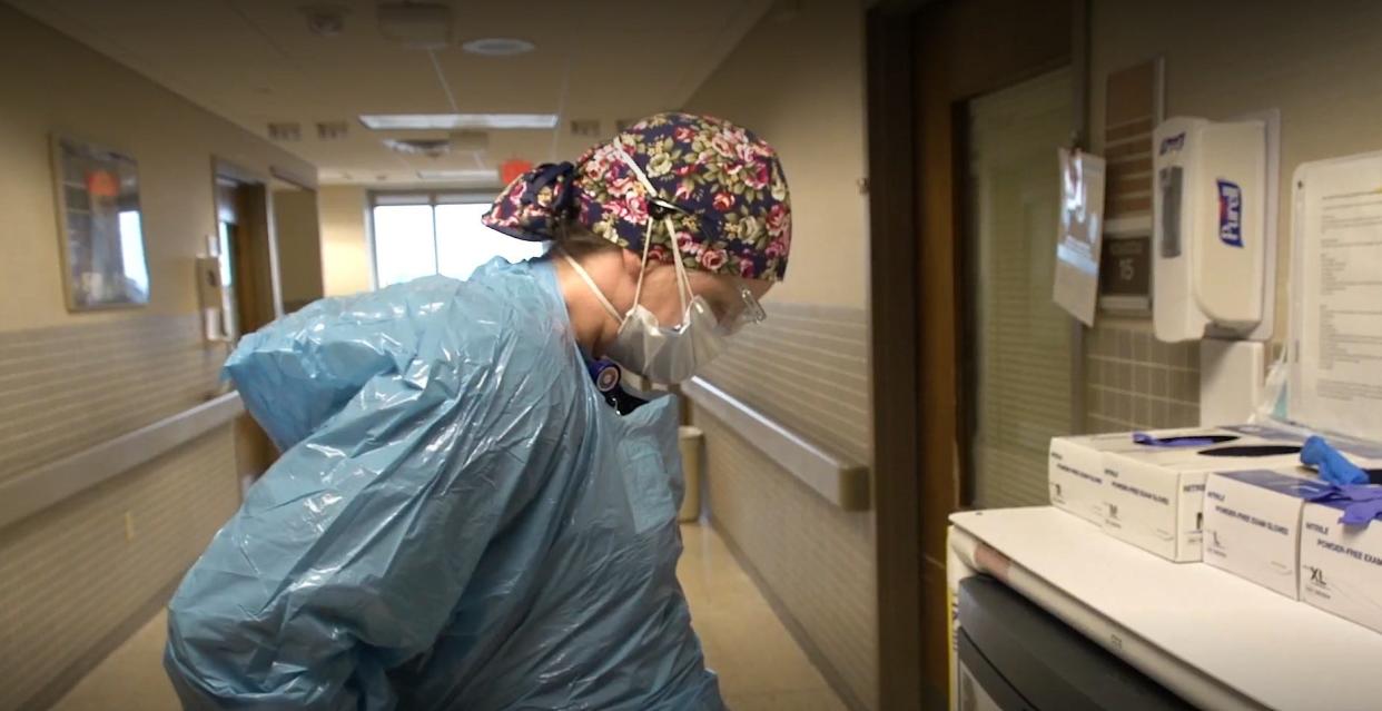 A nurse dons personal protective equipment (PPE) in the ICU at HSHS St. Vincent Hospital in Green Bay.