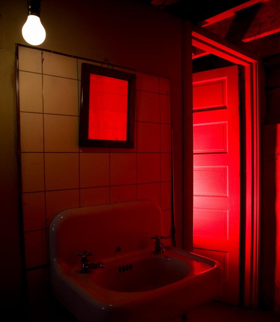 A bathroom sink is bathed in an eerie red light