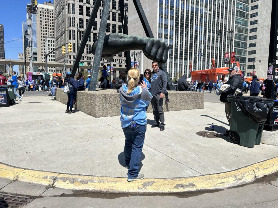 Lions fans get an essential Detroit photo by The Fist sculpture on Jefferson Avenue near the NFL Draft Experience in Hart Plaza on the first day of the NFL draft.