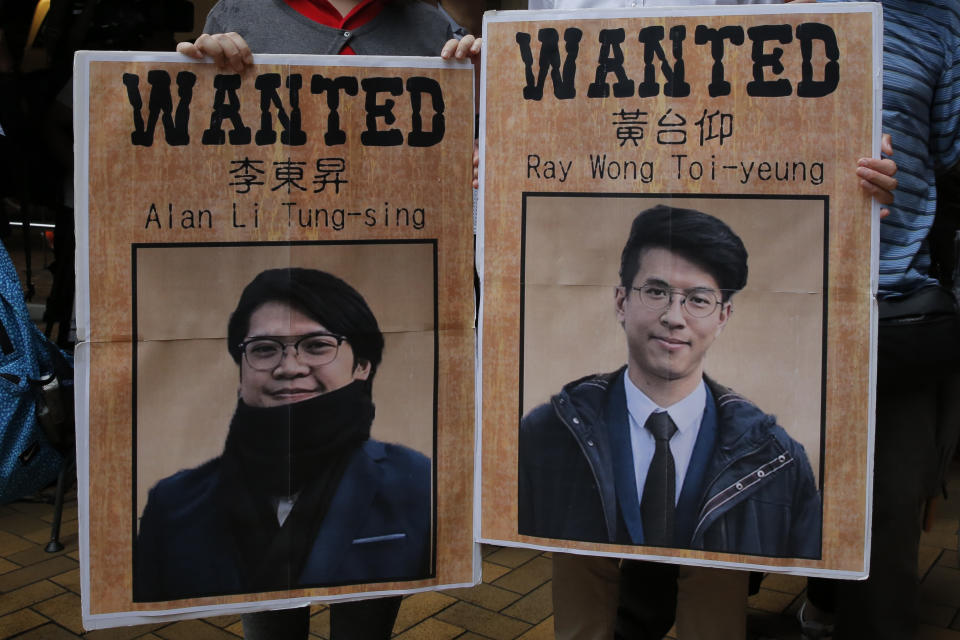 Pro-China protesters hold pictures of Hong Kong activists Ray Wong Toi-yeung, right, and Alan Li Tung-sing during a demonstration near the German Consulate General Consulate in Hong Kong to against Germany in granting a refugee status for the Hong Kong activists, Thursday, May 23, 2019. Germany has granted asylum to two Hong Kong activists in a sign of growing concern over how dissent is dealt with in the territory. (AP Photo/Kin Cheung)