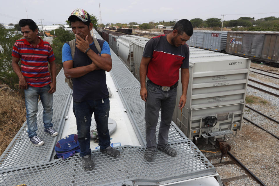 Honduran migrants Jose Francisco Mendez, left, Denis Funes, center, and Jose Mendoza stand on top of a freight train during their journey toward the U.S.-Mexico border, in Ixtepec, Oaxaca State, Mexico, Tuesday, April 23, 2019. Funes says he saw a fellow Honduran knocked off the train the previous night by a low-hanging branch that caught the man in the face and sent him hurtling to the tracks below. (AP Photo/Moises Castillo)