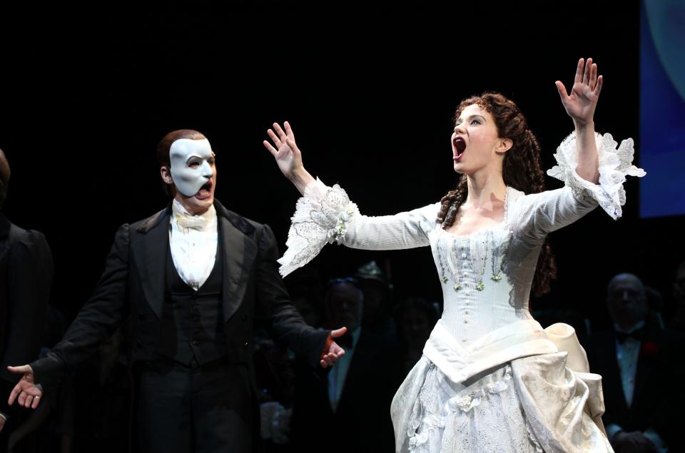 A woman sings to the crowd in costume while a man in a mask sings to her