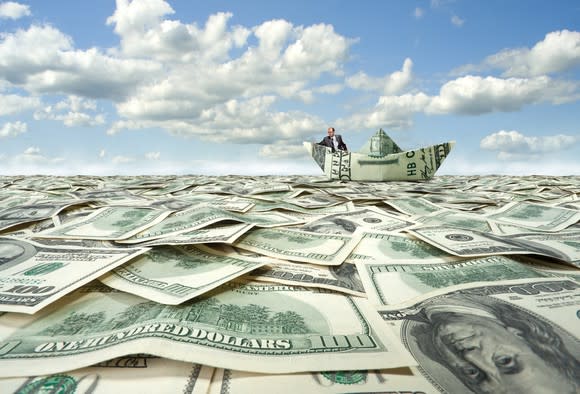 Man in boat made of money on sea of cash