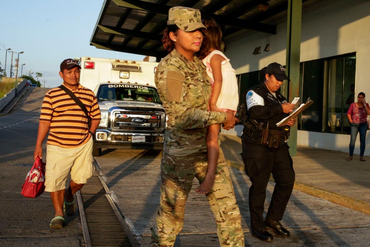 Jose Gonzalez, left, follows his 5-year-old daughter, carried by a police officer, as they leave a hospital in Santiago, Panama. Gonzalez's wife and five of their children are among seven people killed in a religious ritual in the Ngabe Bugle indigenous community: AP