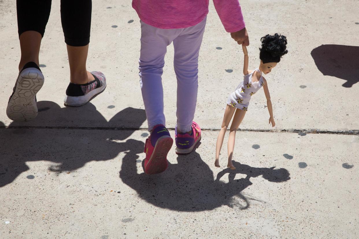 A 4-year-old Honduran girl carries a doll while walking with her immigrant mother, both released from detention: LOREN ELLIOTT/AFP/Getty Images