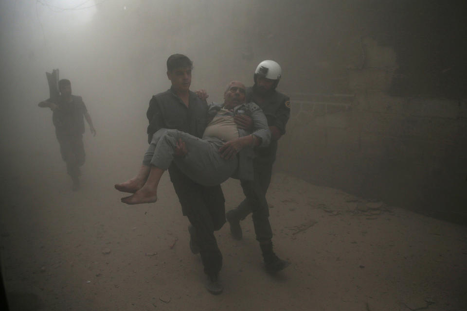 Civil defense members carry an injured man after an air strike in Damascus