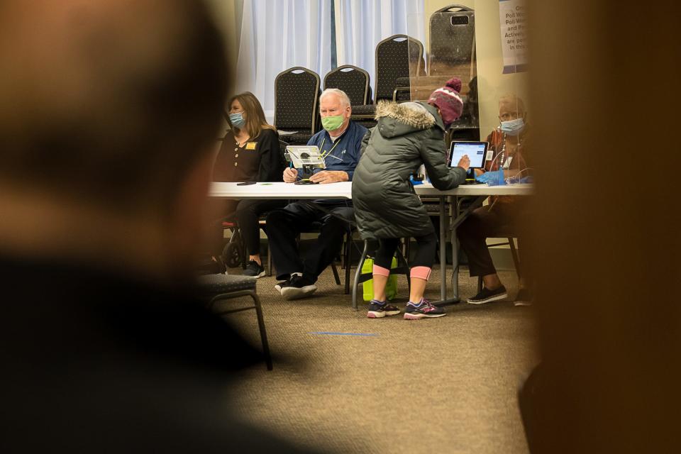 Voters check in with poll workers as they prepare to cast their ballots Tuesday morning at Coastal Cathedral Church.