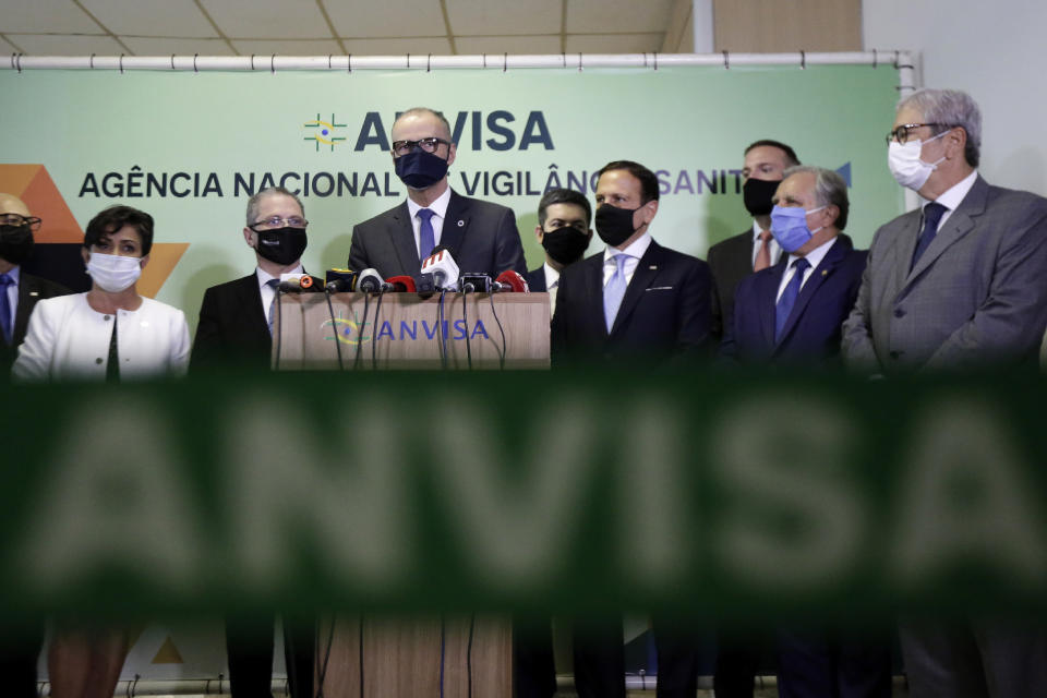 The Director of Brazil's National Health Surveillance Agency Antonio Barra speaks at a press conference regarding the CoronaVac vaccine, flanked by Sao Paulo Gov. Joao Doria, right center, in Brasilia, Brazil, Wednesday, Oct. 21, 2020. Brazil’s President Jair Bolsonaro rejected on Wednesday the announced purchase of 46 million doses of the potential vaccine being developed by a Chinese company and tested in Sao Paulo, a state governed by his political rival, prompting concern he was allowing politics to steer public health decisions. (AP Photo/Eraldo Peres)