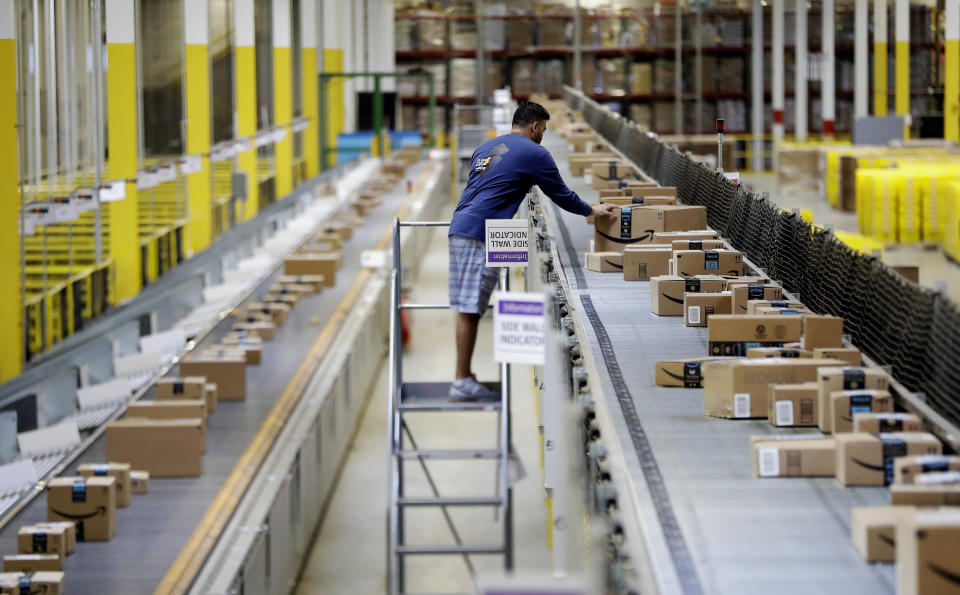 FILE - In this Tuesday, Aug. 1, 2017, photo, an Amazon employee makes sure a box riding on a belt is not sticking out at the Amazon Fulfillment center in Robbinsville Township, N.J. Amazon failed to properly record work-related injuries at warehouses located in five states, a federal agency said Friday, Dec. 16, 2022, while announcing it issued more than a dozen citations during the course of its ongoing investigation of the company. (AP Photo/Julio Cortez, File)