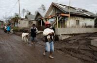 Misto Pakferi, 47, carries his goat as locals evacuate livestock in an area affected by the eruption of Mount Semeru volcano in Curah Kobokan village, Pronojiwo district, in Lumajang, Indonesia