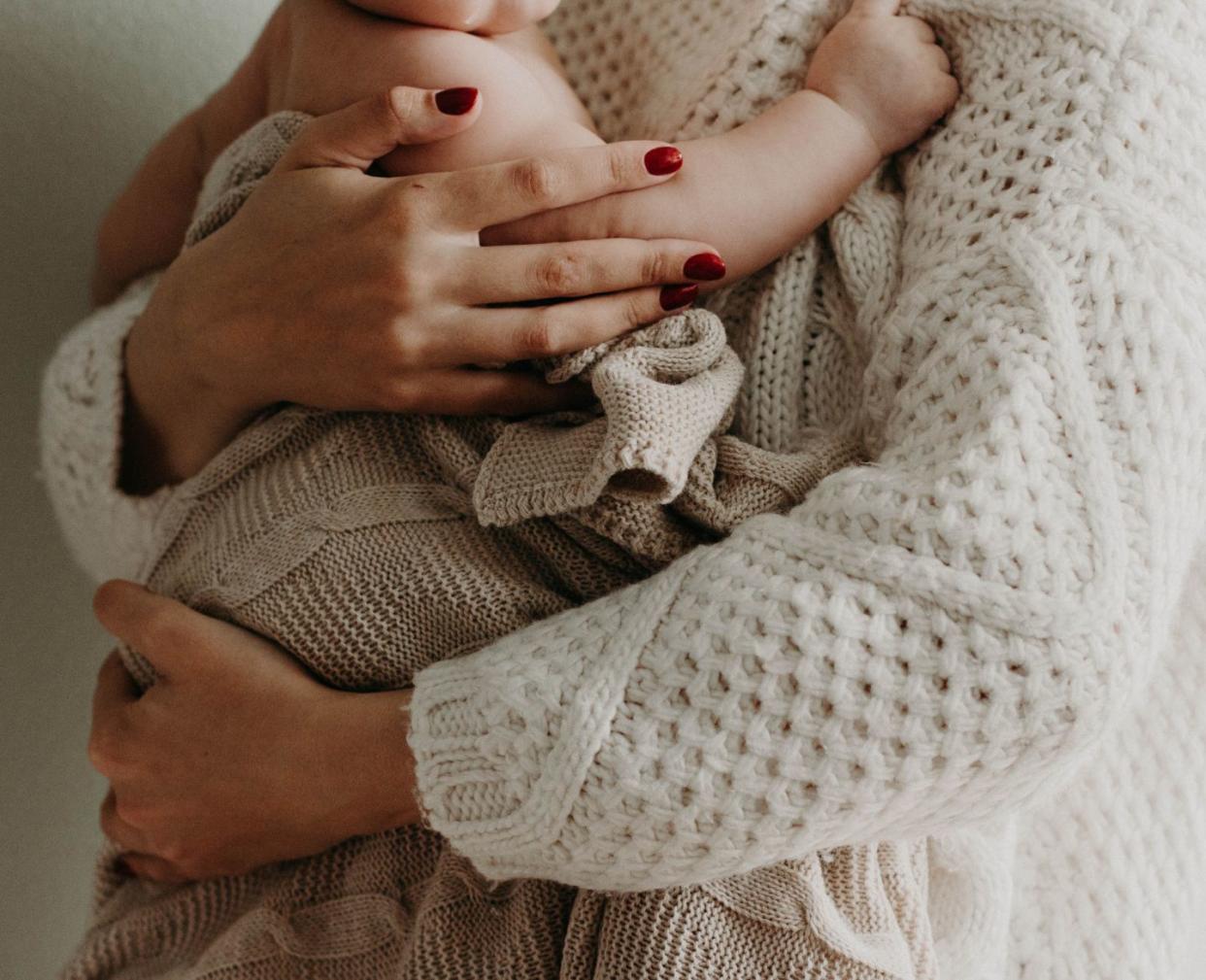 woman holding baby against her chest wrapped in a blanket