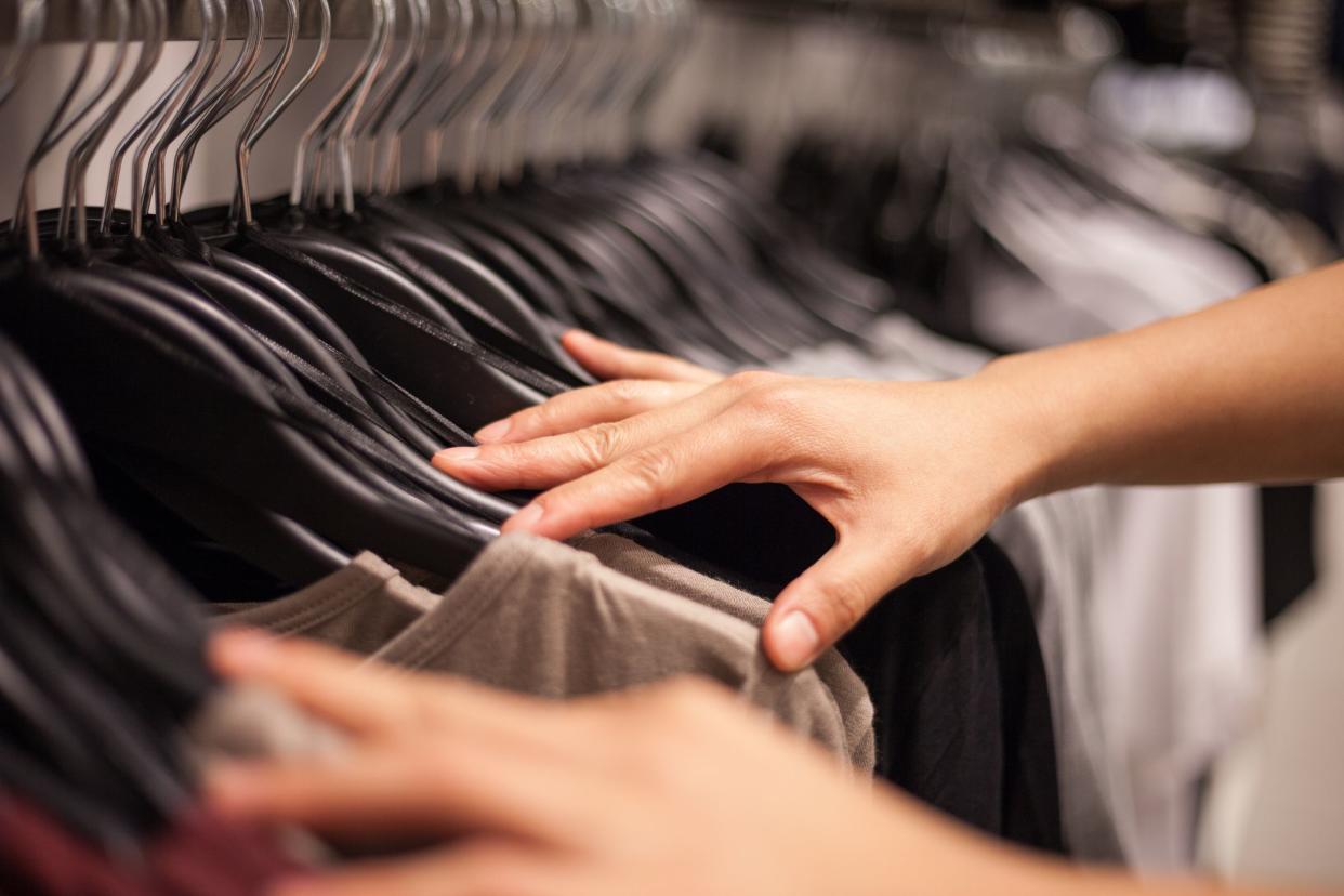 Closeup of woman's hands selecting cloths in fashion store.