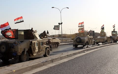 A convoy of Iraqi military trucks flying religious Shia flags and Iraqi national flag as they advance into the central of Kirkuk city, northern Iraq - Credit: EPA