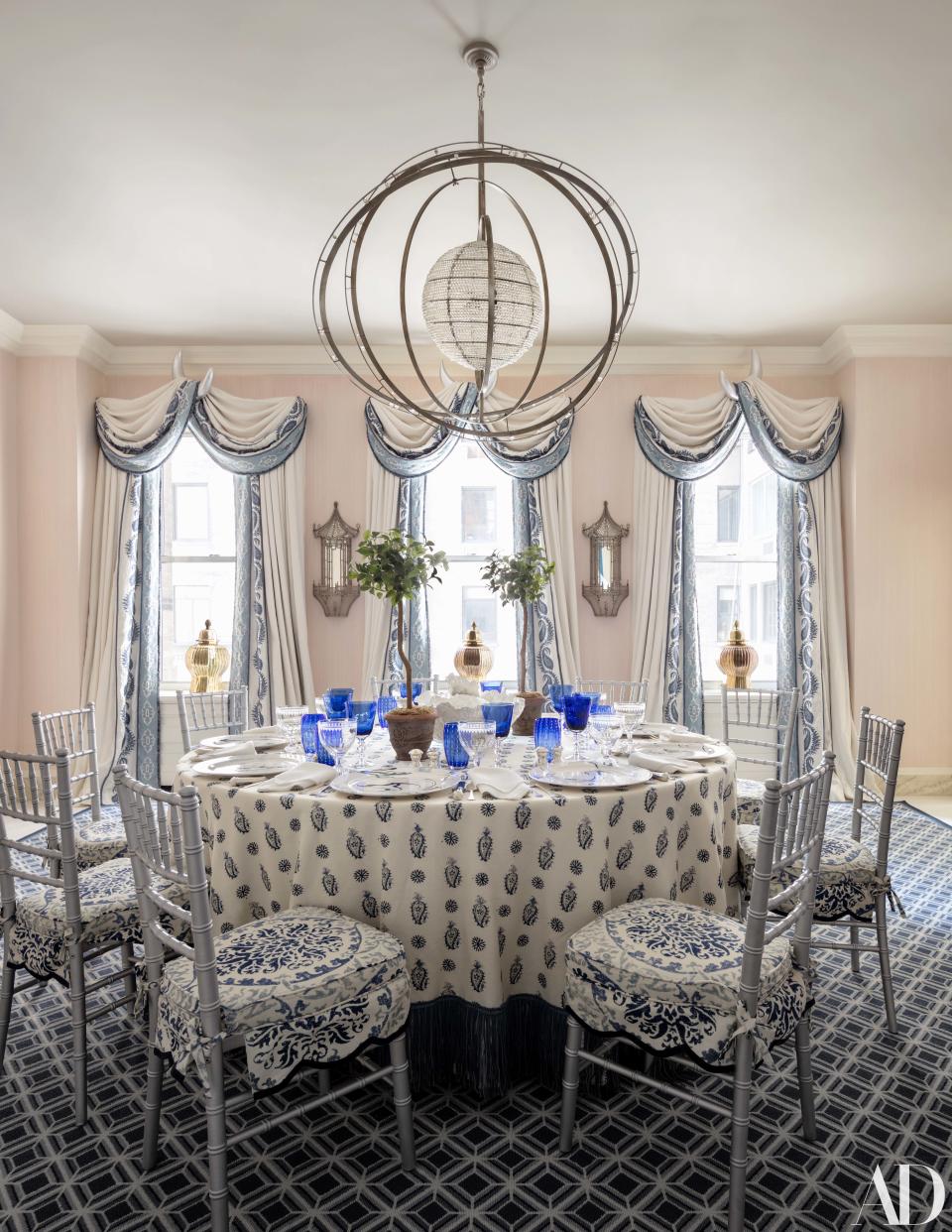 In the dining room, a hanging light from John Rosselli illuminates a table draped in a Brunschwig & Fils fabric. Curtains of a Lee Jofa linen; sconces from Liz O'Brien; rug by Stark.