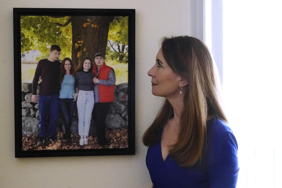 Maura Sullivan looks at a photograph of her children, Tyler, Gillian and Neil, at her home, Friday, March 19, 2021, in Lexington, Mass. The memory of the coronavirus pandemic’s awful toll in nursing homes is still raw. Now, the COVID-19 relief bill is offering states a generous funding boost for home- and community-based care as an alternative to institutionalizing disabled people. “What we really want is that when our loved ones need support, we are going to be able reach out and get that support without another battle,” said Sullivan, who has two sons with autism. “We don’t want to have our kids cut out just because the potholes need to be fixed in the states.” (AP Photo/Charles Krupa)