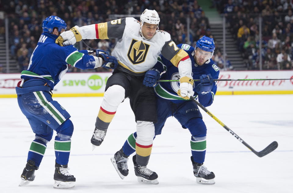 FILE - In this Dec 19, 2019, file photo, Vegas Golden Knights right wing Ryan Reaves (75) jumps to get past Vancouver Canucks defenseman Jordie Benn, left, and center Tyler Motte (64) during the third period of an NHL hockey game in Vancouver, British Columbia. The NHL ditched divisional playoffs to go back to the old-school format for its summer postseason and still ended up with all division rivals facing off in the second round. It’s the Golden Knights against the Canucks in the Pacific series (Jonathan Hayward/The Canadian Press via AP, File)