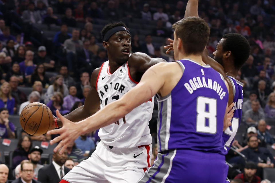 Toronto Raptors forward Pascal Siakam, left, looks to pass as he is double-teamed by Sacramento Kings' Bogdan Bogdanovic, center, and Harrison Barnes, right, during the first quarter of an NBA basketball game in Sacramento, Calif., Sunday, March 8, 2020. (AP Photo/Rich Pedroncelli)