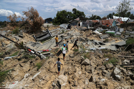 Children walk past an area after an earthquake hit Petobo neighbourhood in Palu, Indonesia, October 6, 2018. REUTERS/Athit Perawongmetha