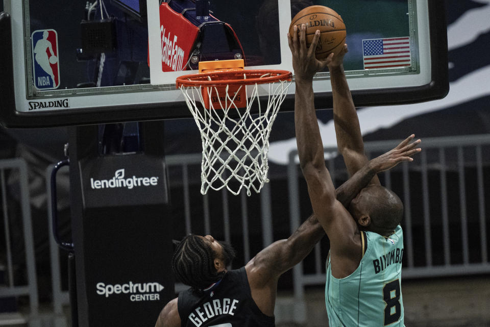 Charlotte Hornets center Bismack Biyombo (8) dunks the ball while guarded by Los Angeles Clippers guard Paul George during the first half of an NBA basketball game in Charlotte, N.C., Thursday, May 13, 2021. (AP Photo/Jacob Kupferman)