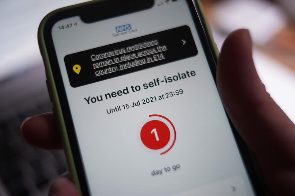 A message to self-isolate, with one day of required isolation remaining, is displayed on the NHS coronavirus contact tracing app on a mobile phone, in London. Picture date: Thursday July 15, 2021.