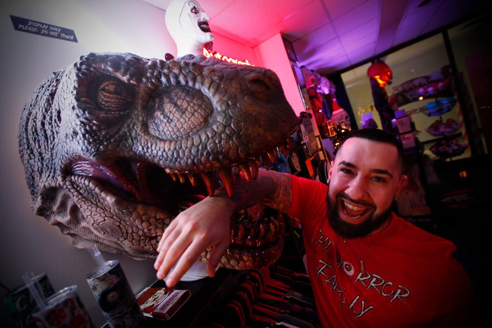 Matt Bassette, owner, has his arm bitten by a T-Rex at the newly opened The Horror Family store on S Sixth Street in downtown New Bedford.