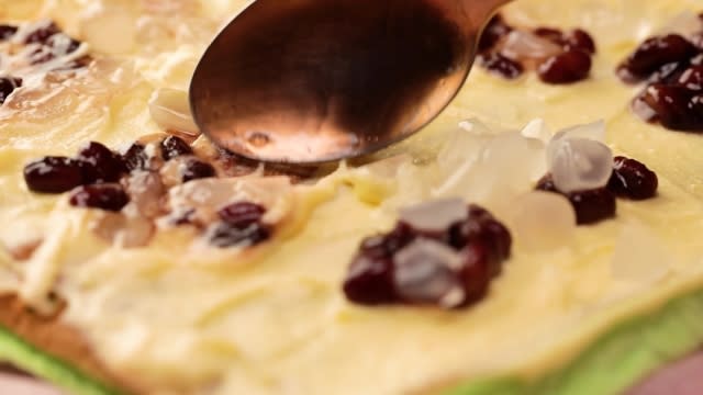 Spreading red beans and atapchi on frosting with spoon