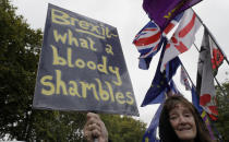 An anti-Brexit demonstrator holds a banner outside Parliament in London, Monday, Oct. 21, 2019. The European Commission says the fact that British Prime Minister Boris Johnson did not sign a letter requesting a three-month extension of the Brexit deadline has no impact on whether it is valid and that the European Union is considering the request. (AP Photo/Kirsty Wigglesworth)