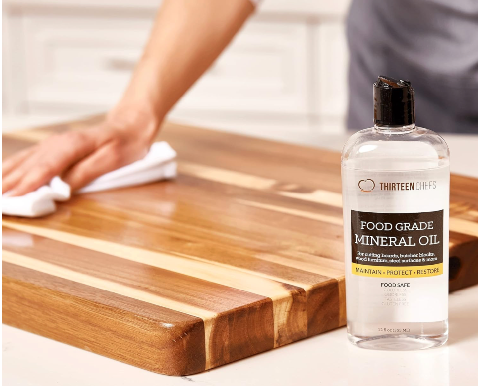  A 12-ounce bottle of Thirteen Chefs Food Grade Mineral Oil being used to seal a butcher block cutting board.