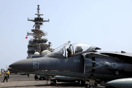 A U.S. Marine maintains an AV-8B Harrier aircraft on the flight deck of USS Boxer (LHD-4) in the Arabian Sea off Oman