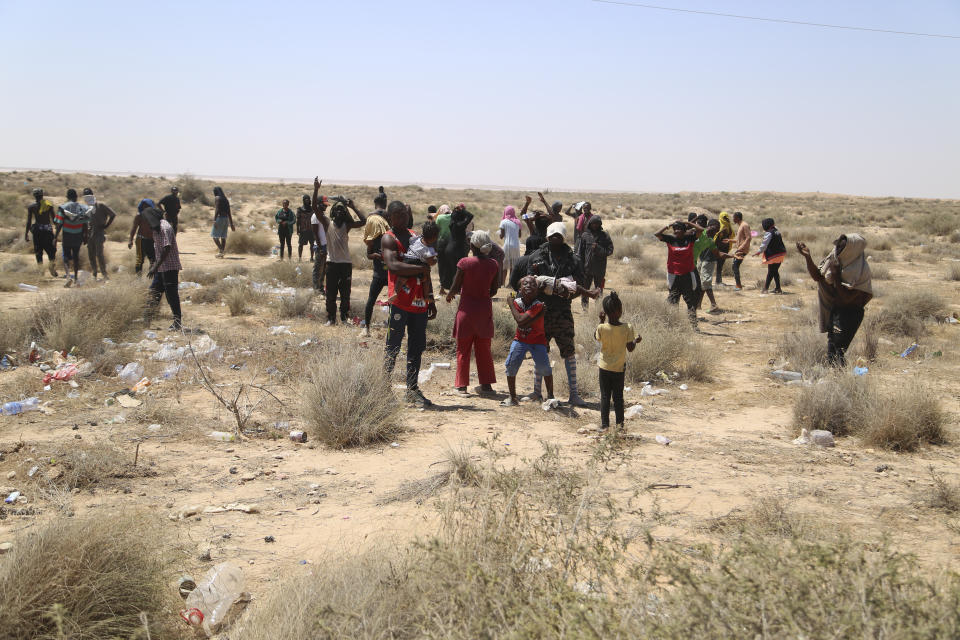 African migrants stand on the Libyan border with Tunisia on Thursday, Aug. 4, 2023. The Tunisian security forces reportedly expelled hundreds of migrants over the border into Libya, where they have been stranded in scorching summer temperatures without water and food since June. (AP Photo/Yousef Murad)