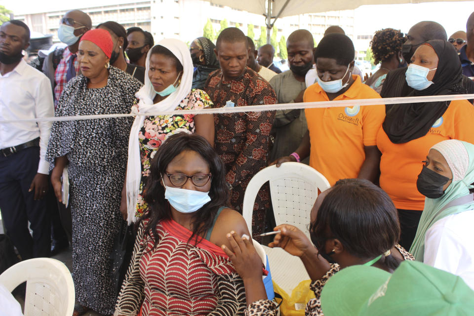 A Nigeria civil servant receives a dose of the AstraZeneca coronavirus vaccine, before she is allow access to her office in Abuja, Nigeria , Wednesday, Dec. 1, 2021. Nigeria has detected its first case of the omicron coronavirus variant in a sample it collected in October, weeks before South Africa alerted the world about the variant last week, the country's national public health institute said Wednesday. (AP Photo/Gbemiga Olamikan)