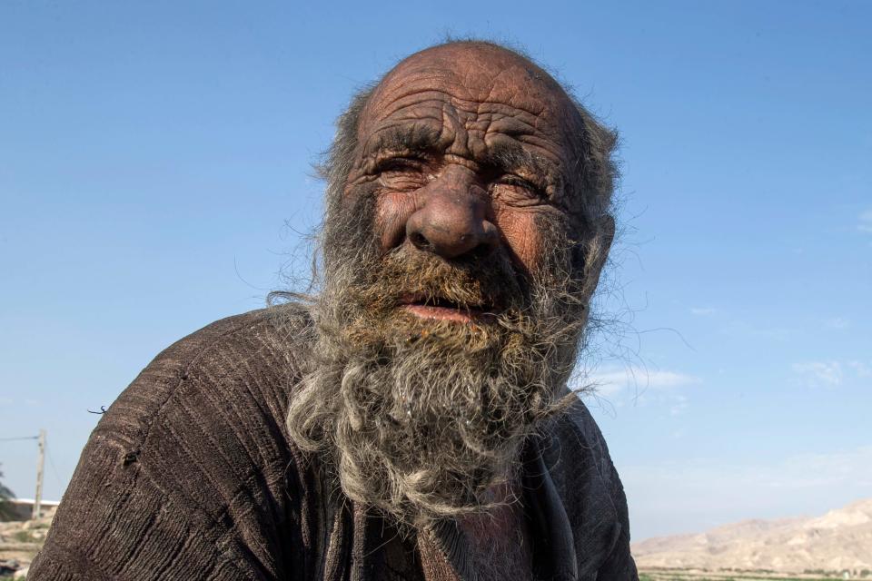 In this file photo taken on December 28, 2018 Amou Haji (uncle Haji) sits on the outskirts of the village of Dezhgah in the Dehram district of the southwestern Iranian Fars province. - An Iranian dubbed the "dirtiest man in the world" for not taking a shower for decades has died at the age of 94, state media said on October 25, 2022.