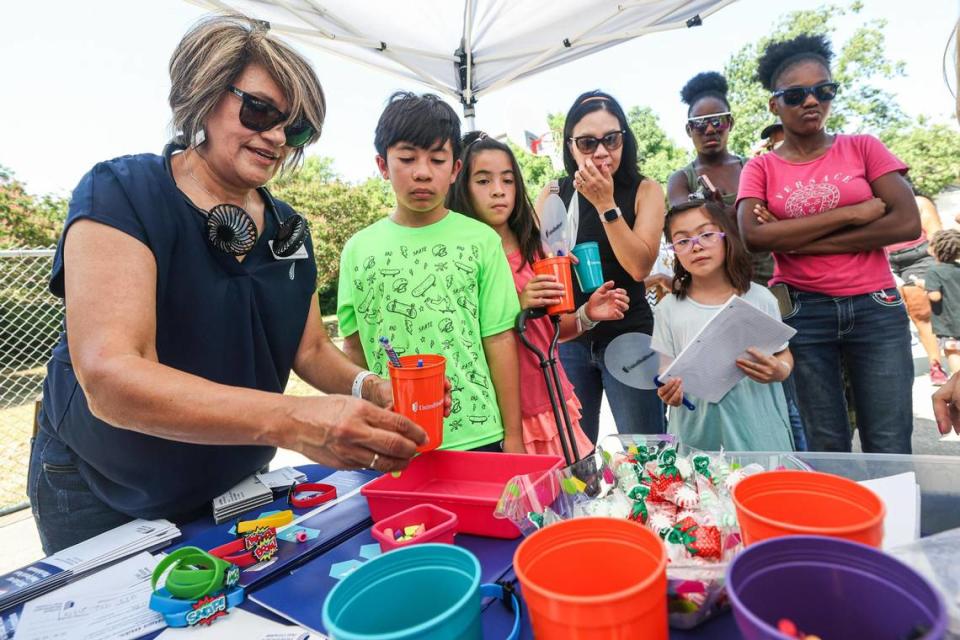 Padres y niños hacen fila para recibir material escolar gratuito de manos de Lucy Whitley, agente de ventas de United Health Care, durante la fiesta anual de regreso a la escuela en el Thomas Place Community Center, en Fort Worth, el 26 de julio.