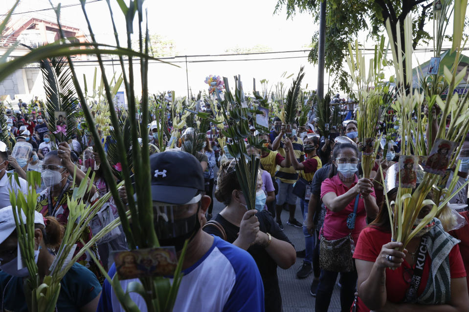 Devotees wearing face masks and face shields to prevent the spread of the coronavirus attends a Palm Sunday mass, March 28, 2021 outside the Saint Peter Parish Church in Quezon city, Philippines. The government banned religious activities during the Holy Week as it enters into stricter lockdown measure starting next week while country struggles to control an alarming surge in COVID-19 cases. (AP Photo/Aaron Favila)