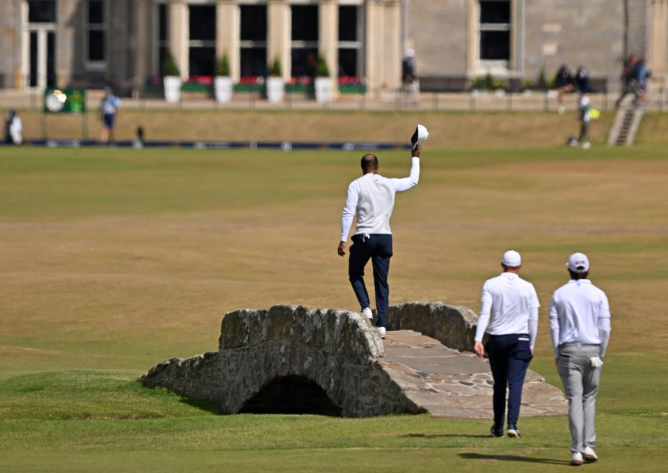 US golfer Tiger Woods gestures to the crowd as he walks over the Swilcan Bridge on the 18th hole, followed by England's Matthew Fitzpatrick (2nd R) and US golfer Max Homa (R) during his second round on day 2 of The 150th British Open Golf Championship on The Old Course at St Andrews in Scotland on July 15, 2022. - RESTRICTED TO EDITORIAL USE (Photo by Glyn KIRK / AFP) / RESTRICTED TO EDITORIAL USE (Photo by GLYN KIRK/AFP via Getty Images)