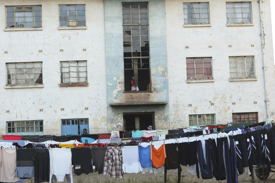 A girl stands on a balcony at a block of flats in Harare, Thursday, Aug, 8, 2019. The sight of Harare residents walking home at dusk carrying firewood and water buckets has become common as the country struggles with water and power crisis. (AP Photo/Tsvangirayi Mukwazhi)