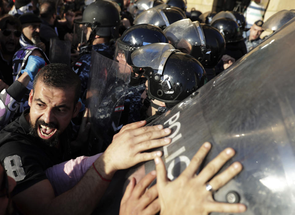 Anti-government protesters scuffle with riot police during a protest in downtown Beirut, Lebanon, Tuesday, Nov. 19, 2019. Scuffles have broken out in central Beirut as hundreds of anti-government protesters tried to prevent lawmakers from reaching Parliament. (AP Photo/Hassan Ammar)