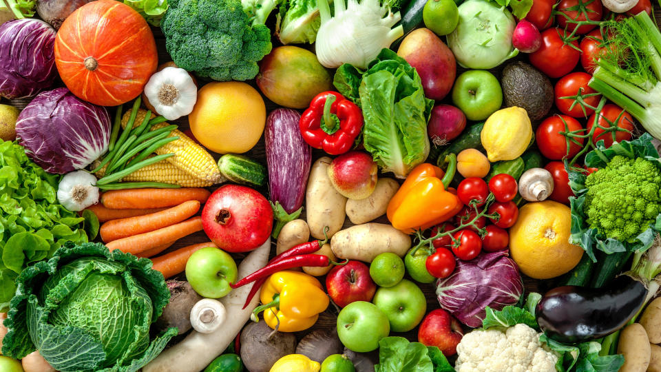 A mixture of fruits and vegetables including carrots, corn, lettuce, apples and bell peppers. (Photo via Getty Images)