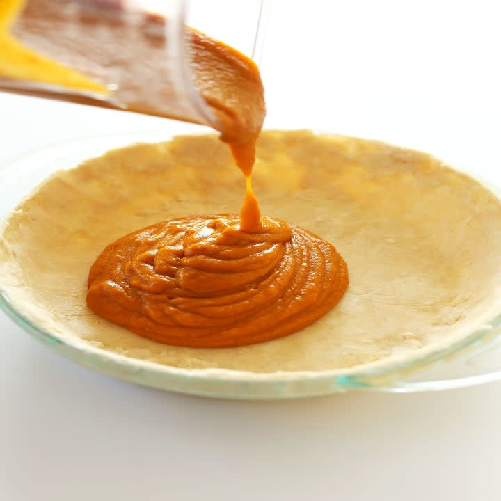 Pouring pumpkin filling into pie crust