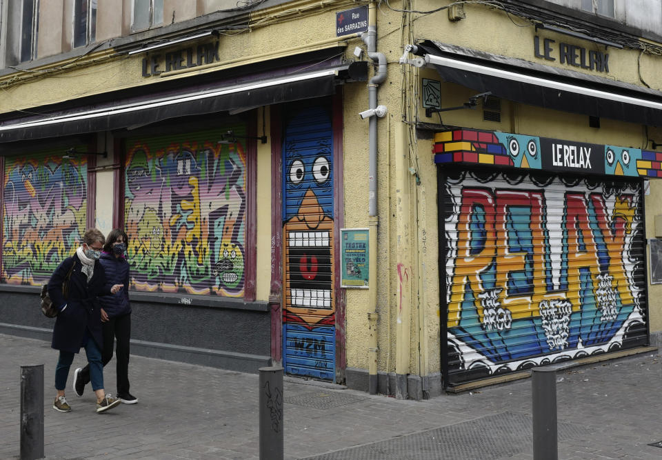 People walk front of a closed cafe in Lille, northern France, Saturday, Oct. 10, 2020. French authorities have placed Lille on maximum virus alert on Monday, banning festive gatherings and requiring all bars to close but allowing restaurants to remain open, as numbers of infections are rapidly increasing. (AP Photo/Michel Spingler)