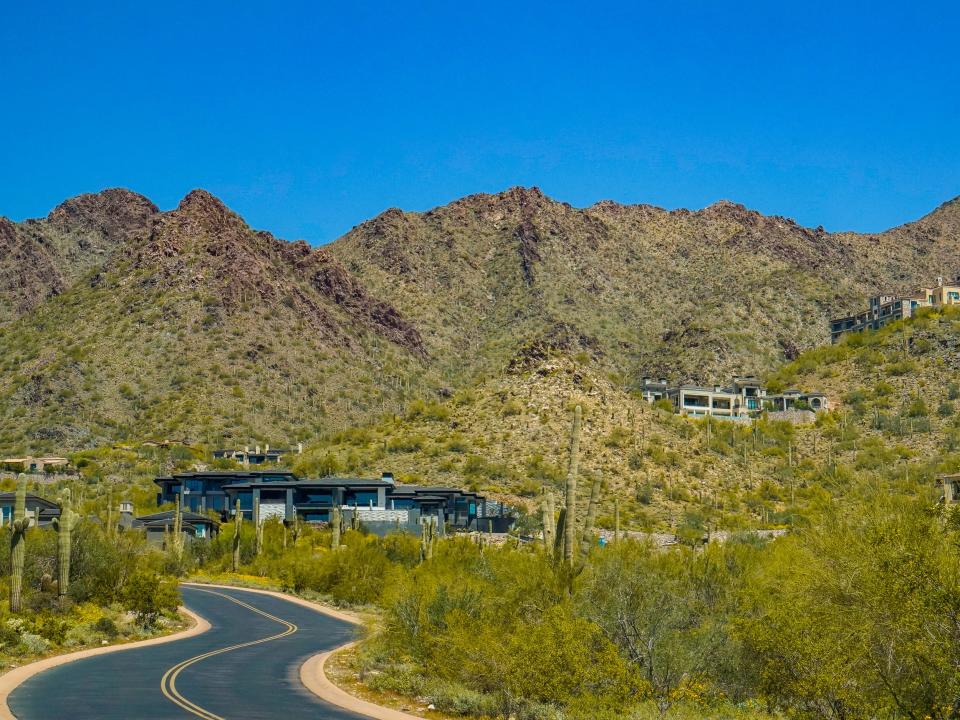 Mansions off of a winding road on a mountain dotted with bushes and cacti in DC Ranch in Scottsdale