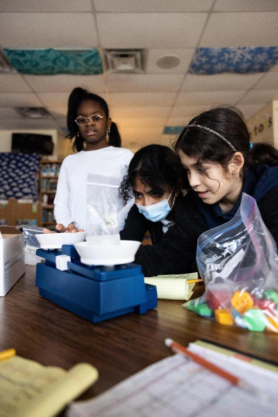 Kyra Baker, 10, from left, Evelyn Mendoza, 11, and Brianna Funez, 11, use a scale during science tutoring at Joseph W. Grier Academy in Charlotte, N.C., on Thursday, March 9, 2023.
