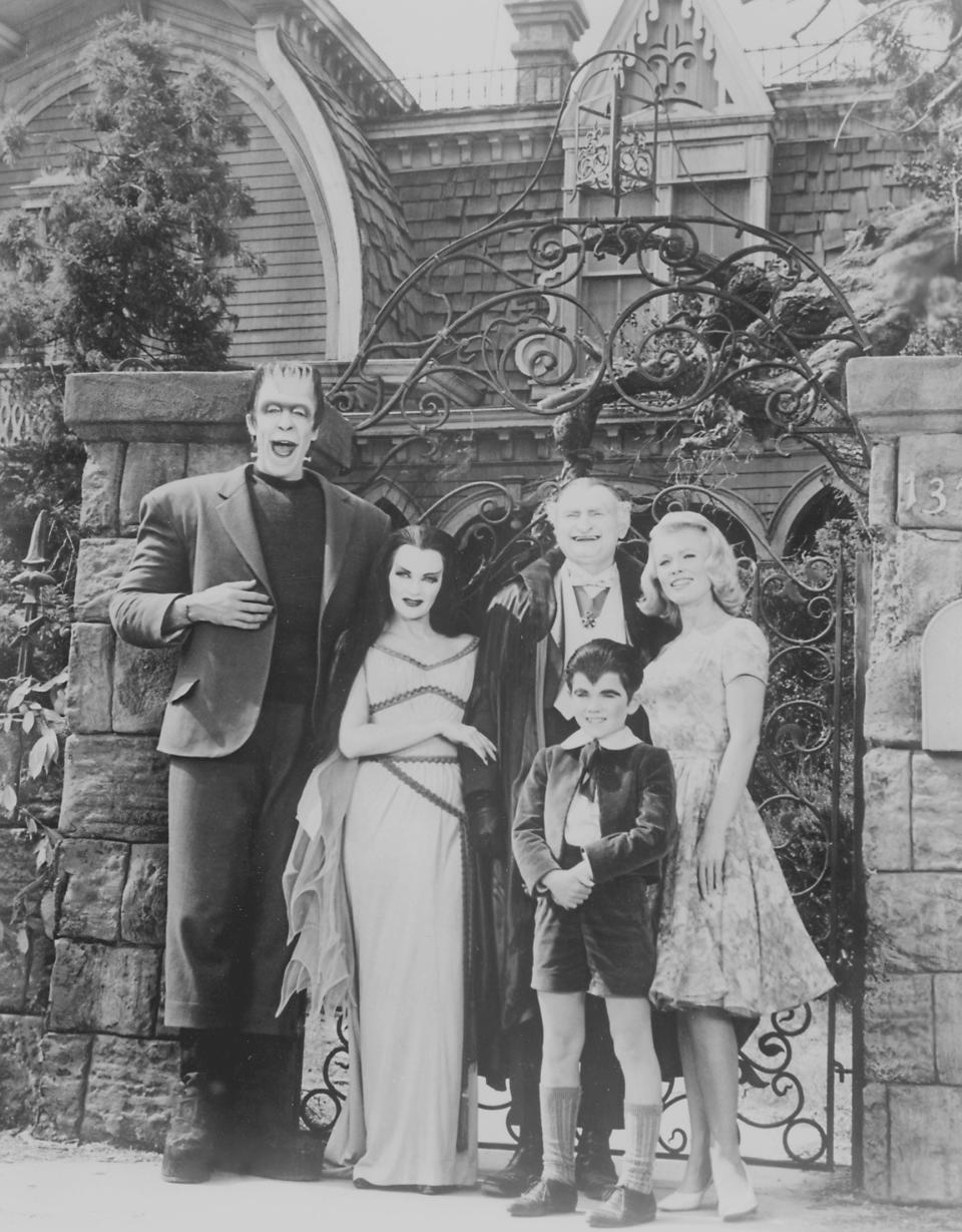 Cast of 'The Munsters' TV show posing in character outside their fictional home