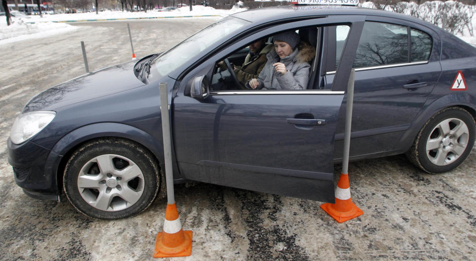 In this photo taken on Monday, Jan. 23, 2012, Natalya Veselova opens a door of her instructor's car at a driving training ground in the south-east of Moscow, Russia. For Veselova, applying for a driver's license has turned into a frustrating ordeal because she refuses to pay the customary bribe. (AP Photo/Mikhail Metzel)