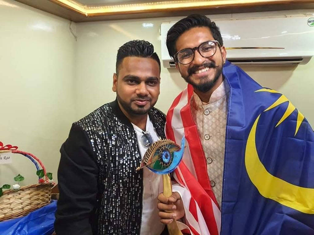 Mugen Rao (R), a Jalur Gemilang (Malaysian flag) draped over his shoulders, proudly holding up his "Bigg Boss" trophy.