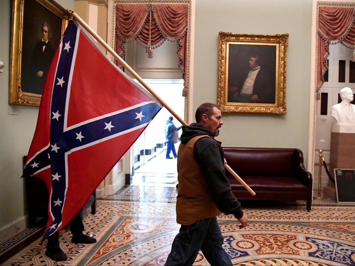 A supporter of President Donald Trump carries a Confederate battle flag on the second floor of the U.S. Capitol near the entrance to the Senate after breaching security defences, in Washington, on 6 January 2021 ((Reuters))