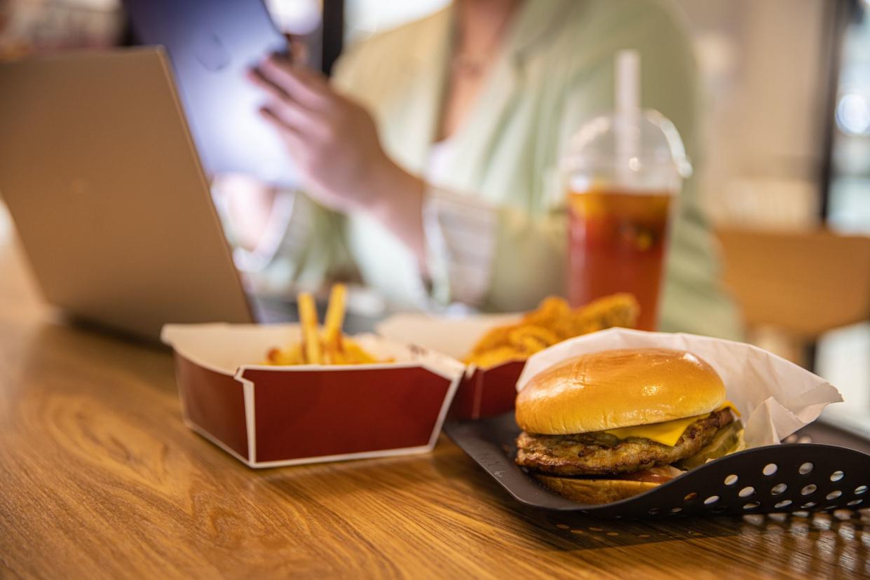 Businesswoman working at laptop with fast food on restaurant table